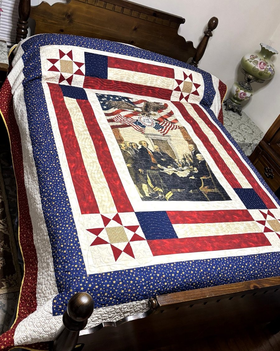 A red, white and blue star quilt on a wooden bed